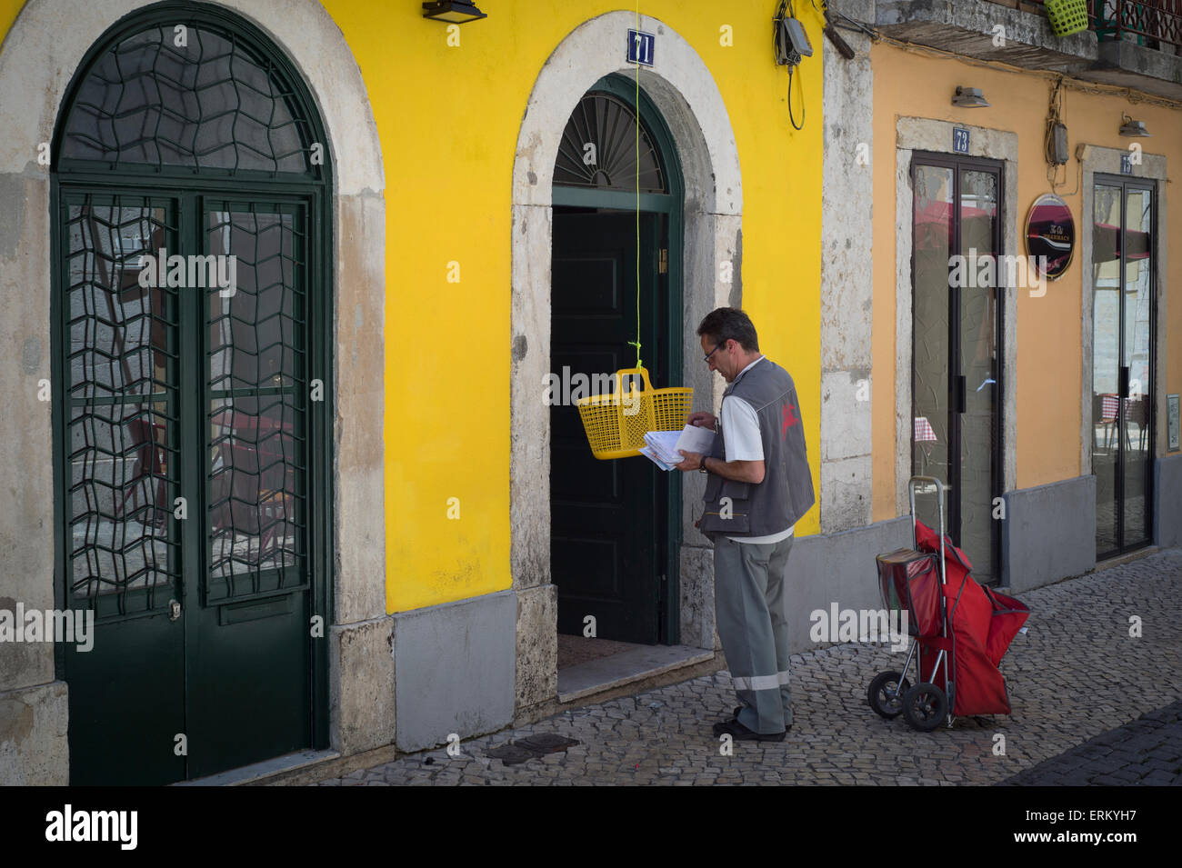 Postbote, der die Post ausliefert, indem er Briefe in einen Korb legt, der dann hochgezogen wird. Lissabon, Portugal. Stockfoto