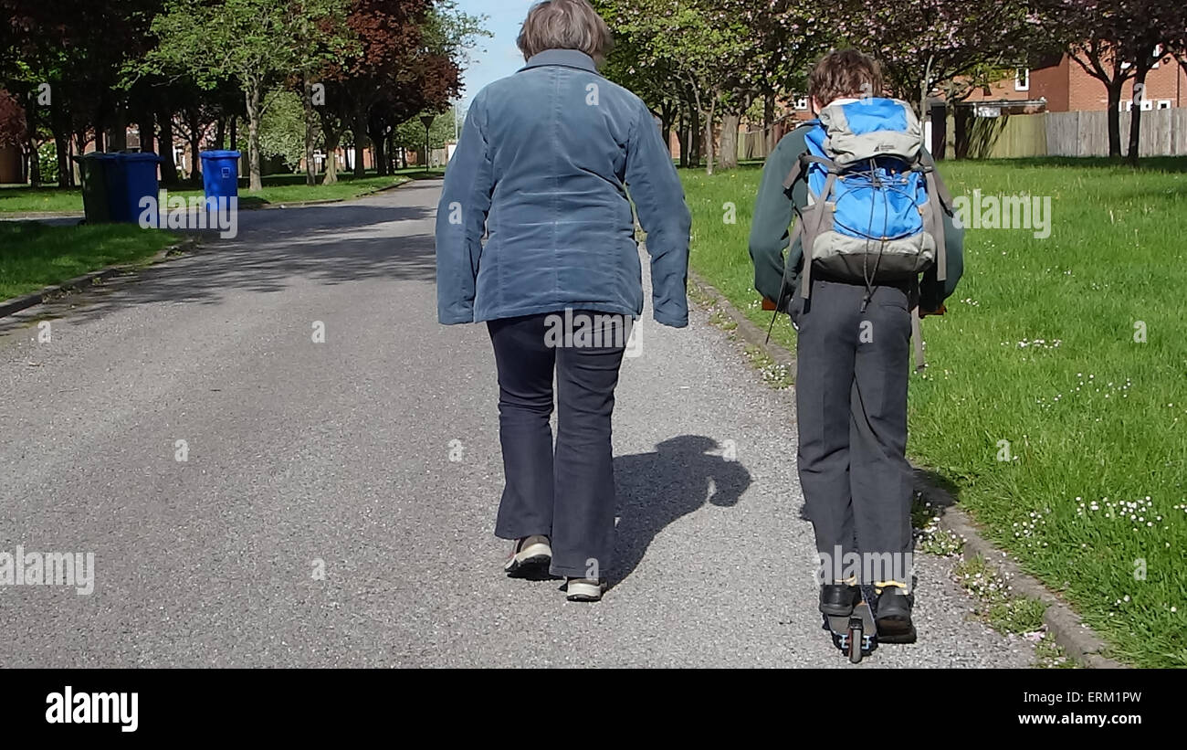 Kleiner Junge geht zur Schule auf Roller mit Großmutter Stockfoto