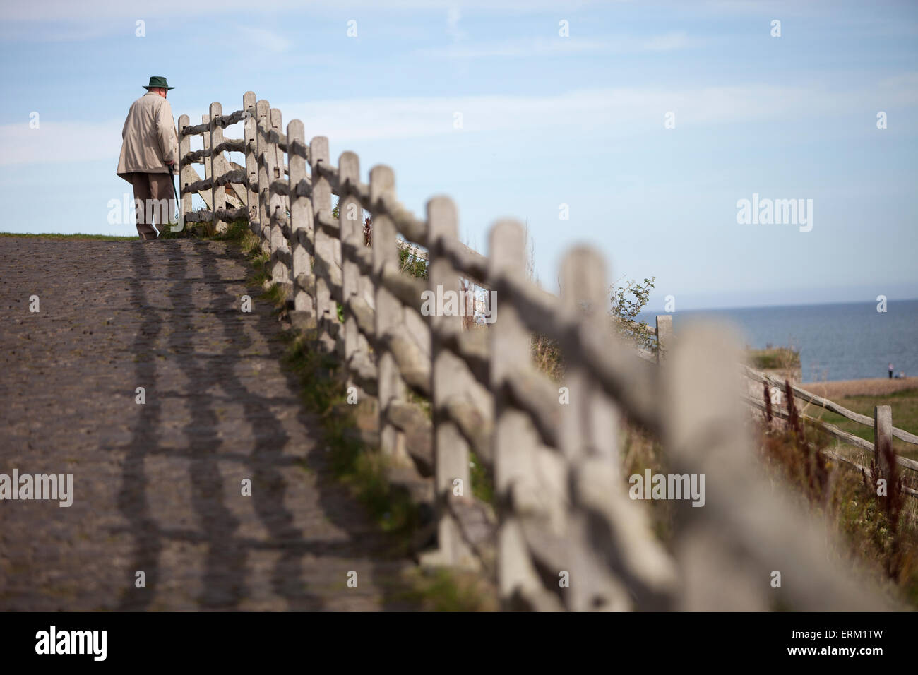 Ein älterer Mann stand auf der Strandpromenade Promenade Blick auf das Meer. Stockfoto