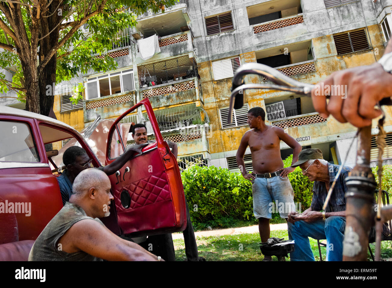 Kubanische Männer reparieren eine amerikanische Oldtimer aus den 1950er Jahren vor dem Wohnblock in Alamar, Havanna, Kuba. Stockfoto