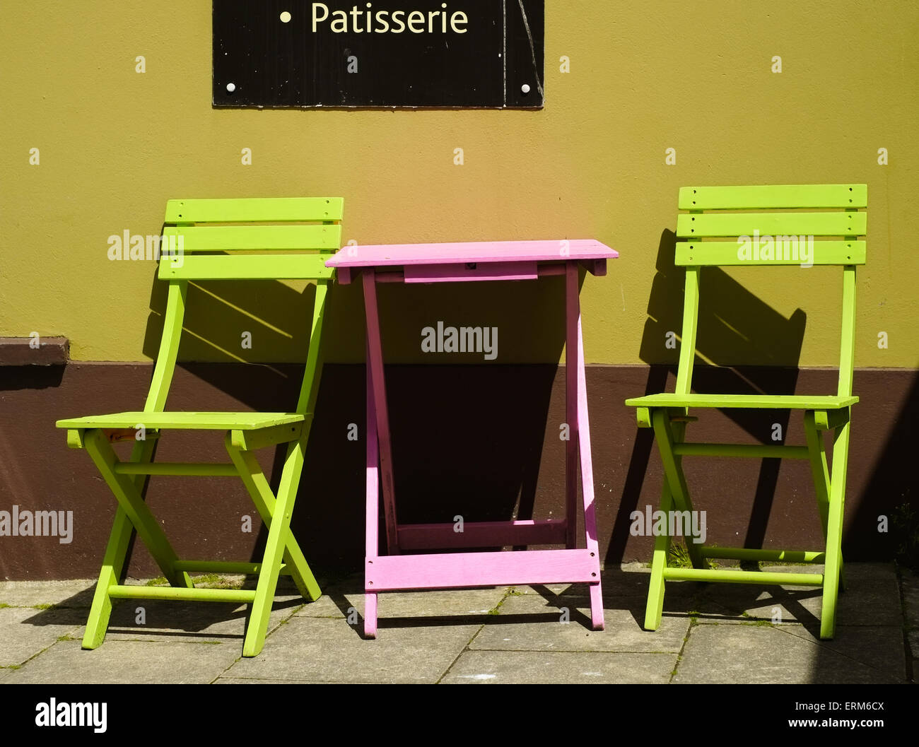 Ein rosa Tisch und zwei lime grüne Stühlen vor einem Café am West St, Fishguard, Pembrokeshire, Wales. Stockfoto