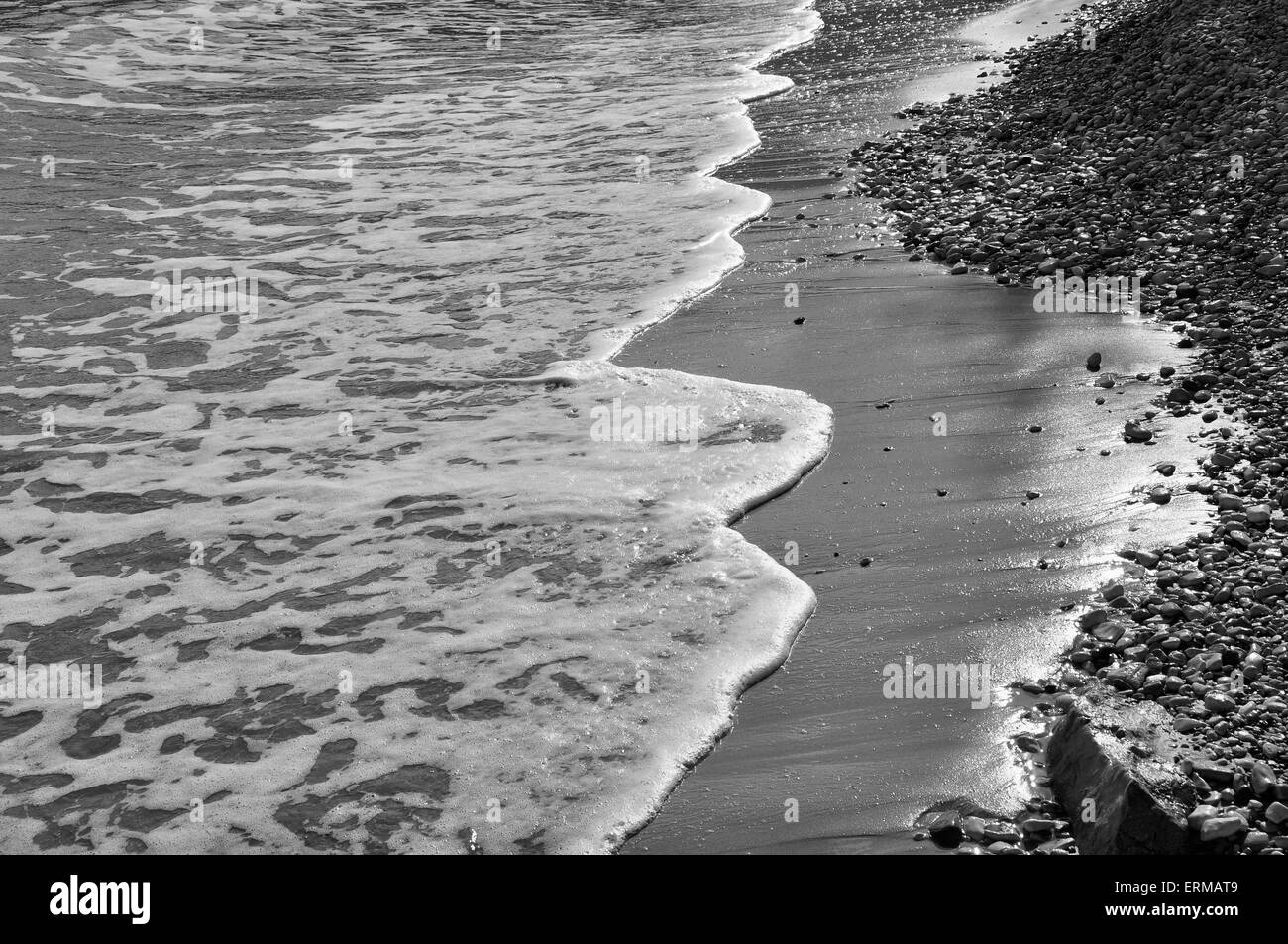 Wellen am Steinstrand Gewässer Rand abstrakte Meer Hintergrund. Schwarz und weiß. Stockfoto
