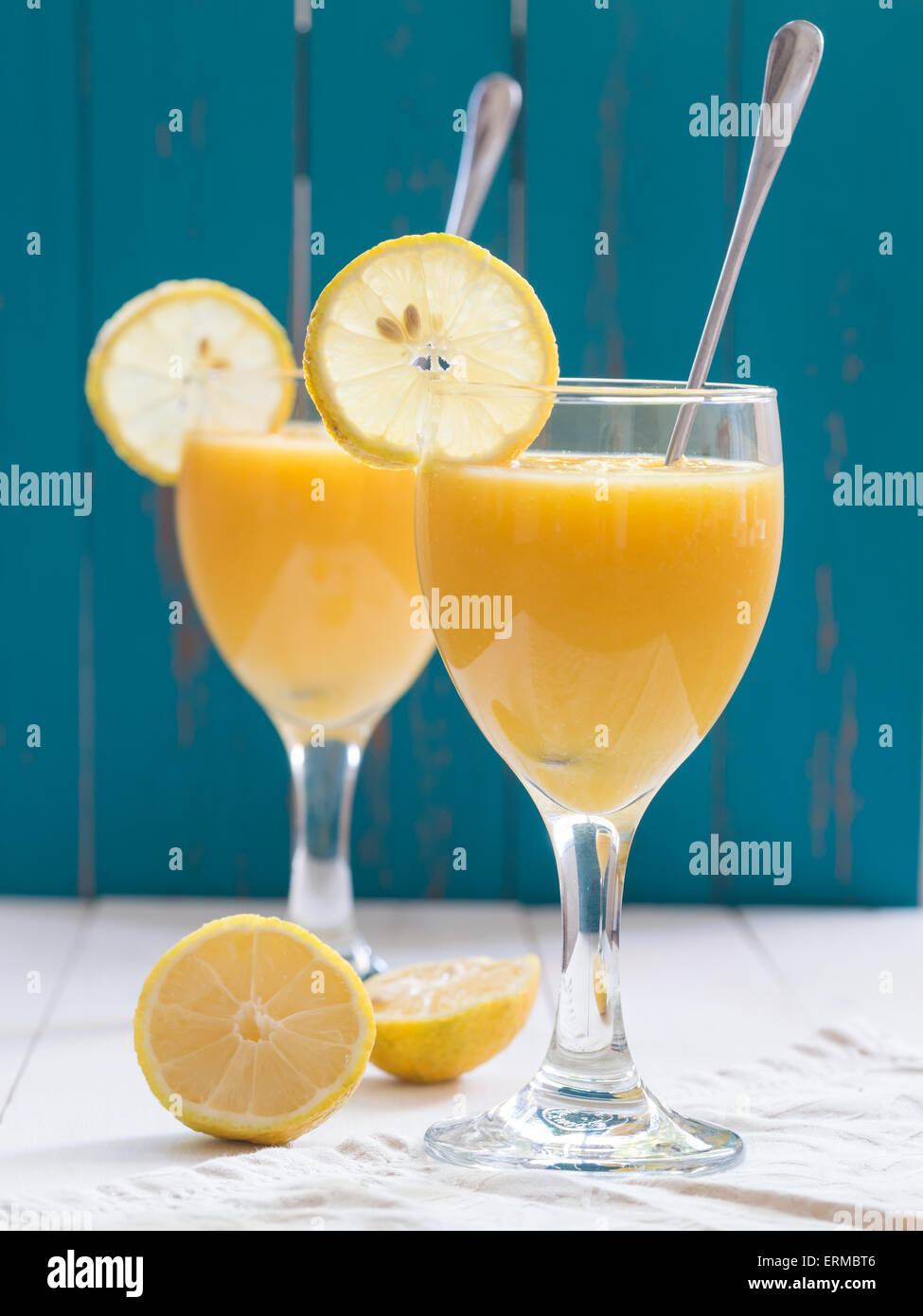 Zwei Gläser Wein von frischen gelben tropischen Frucht-Smoothie mit Mango und Ananas auf einen weißen Tisch platziert. Türkis Hintergrund Stockfoto