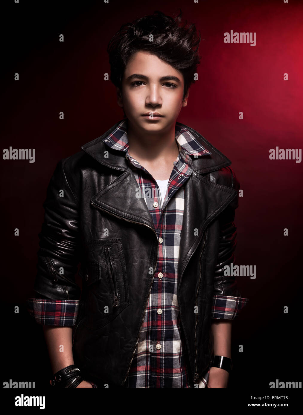 Stilvolle teenboy Porträt über dunkelroten Hintergrund, schönes Modell tragen Mode Hemd und Leder Jacke Stockfoto
