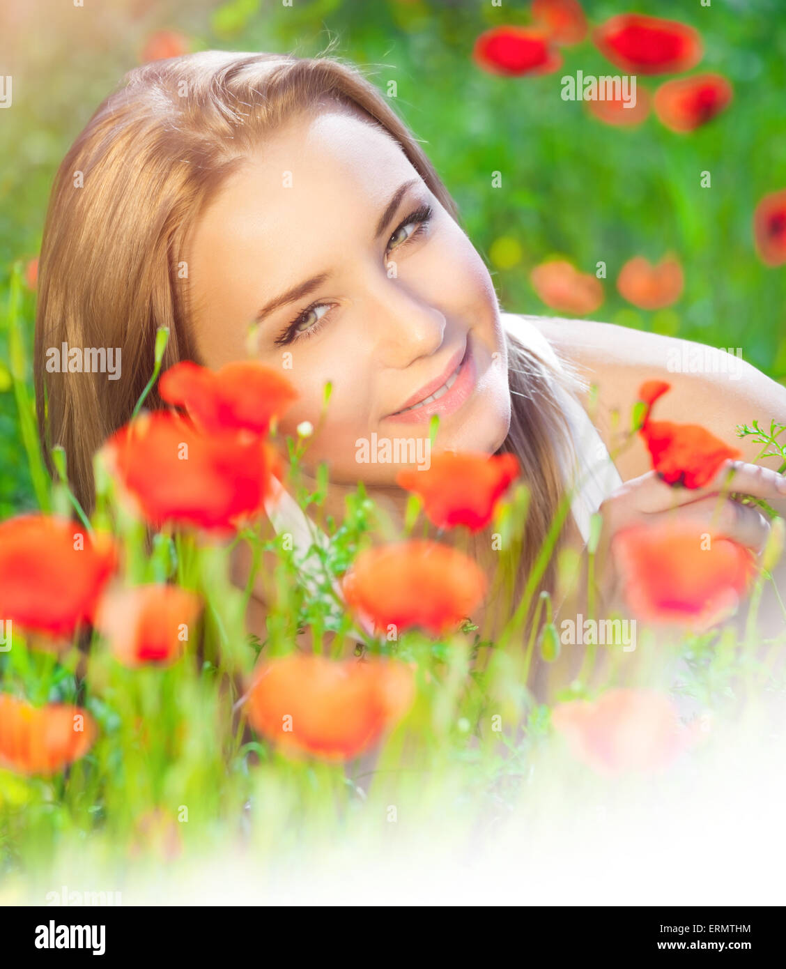 Porträt von Süße blonde Frau liegend auf frischen Mohnfeld, genießen Sie die Schönheit des roten Wildblumen, Foto mit weißen Textfreiraum Stockfoto