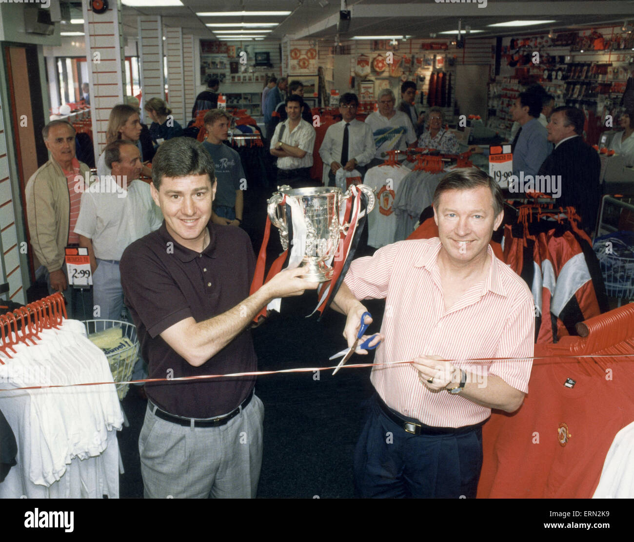 Manchester United-Trainer Alex Ferguson mit Co-Trainer hält den League Cup Trophäe, wie sie eine überarbeitete Red Devils-Souvenir öffnen shop im Old Trafford nach Unterzeichnung merchandising Manager Edward Freeman um ihre Souvenirshop betreiben. Mai 1992. Stockfoto