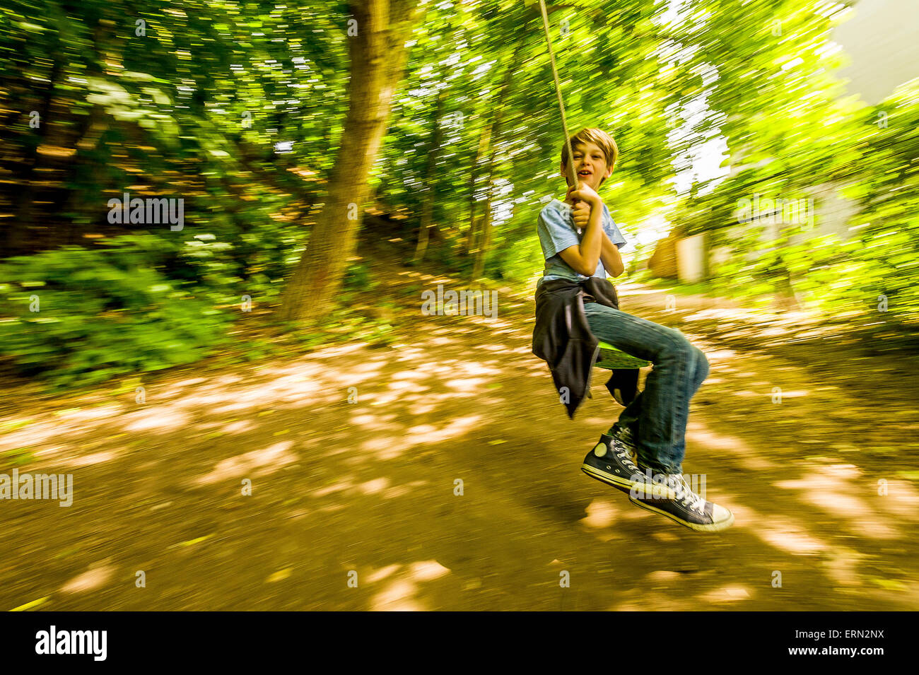 Blonde Junge an der Schaukel sitzend in Holz Stockfoto