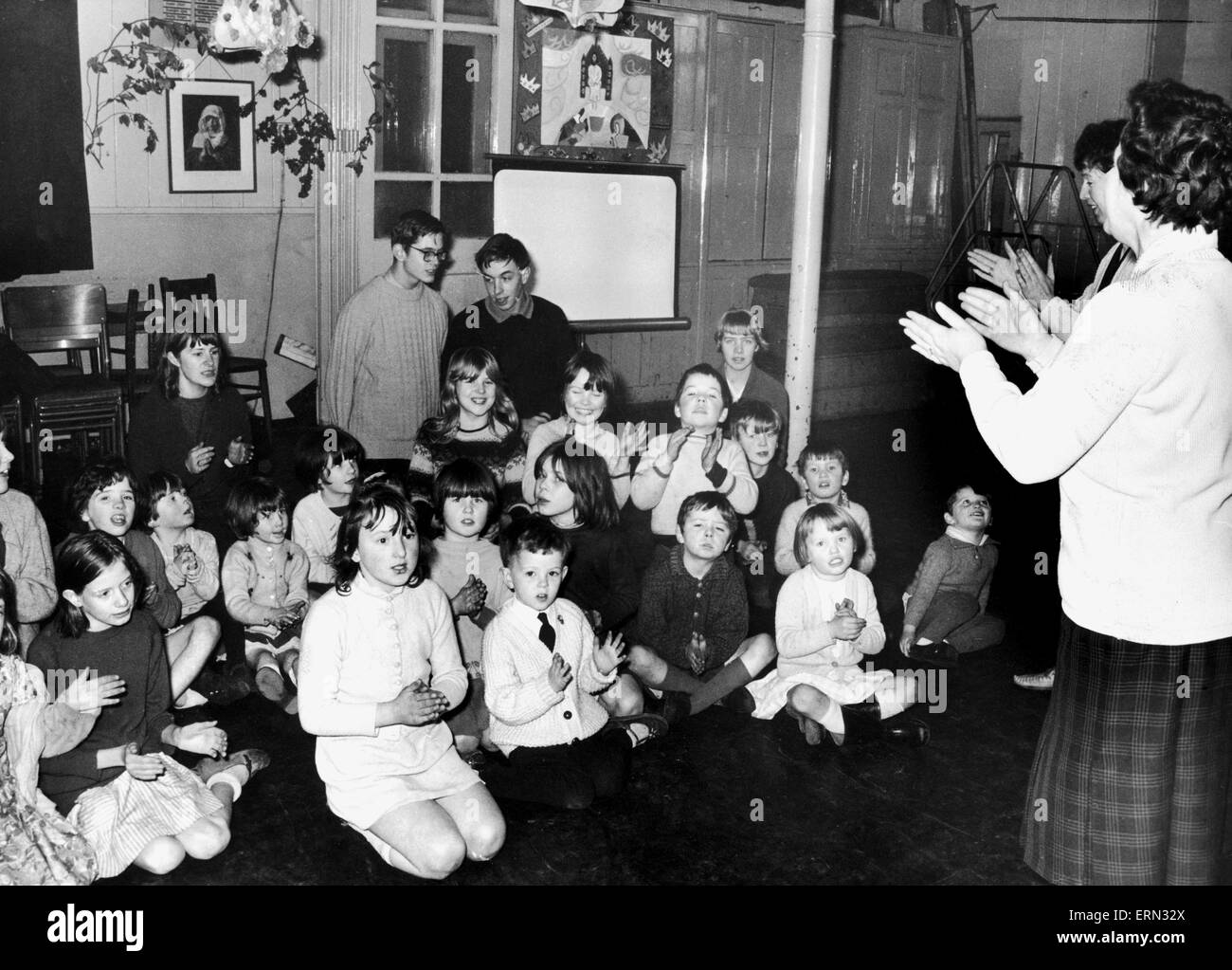 Kinder an einem Singalong-Leitung von Frau Ann Walker teilnehmen und Miss Eileen Williams im Holiday spielen Zentrum an Bischof Ryder Schule, Juwel-Straße. 31. Dezember 1968. Stockfoto