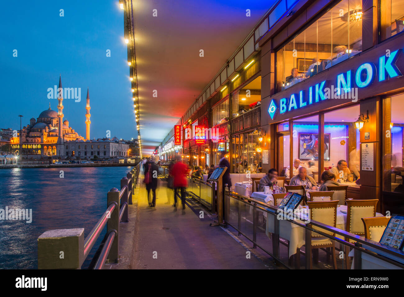 Outdoor-Restaurants unter der Galata-Brücke mit Yeni Cami oder neue Moschee im Hintergrund in der Abenddämmerung, Istanbul, Türkei Stockfoto