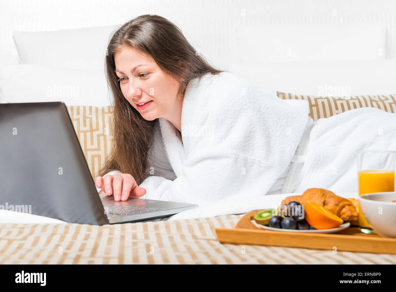 Mädchen auf einem Rechner im Bett am Morgen arbeiten Stockfoto