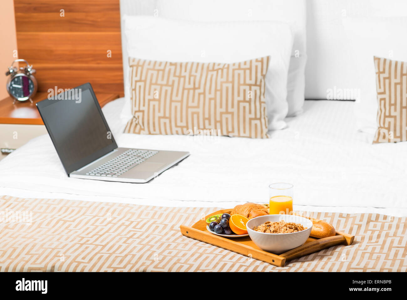 Computer und ein Tablett mit Essen auf dem Bett im Schlafzimmer Stockfoto