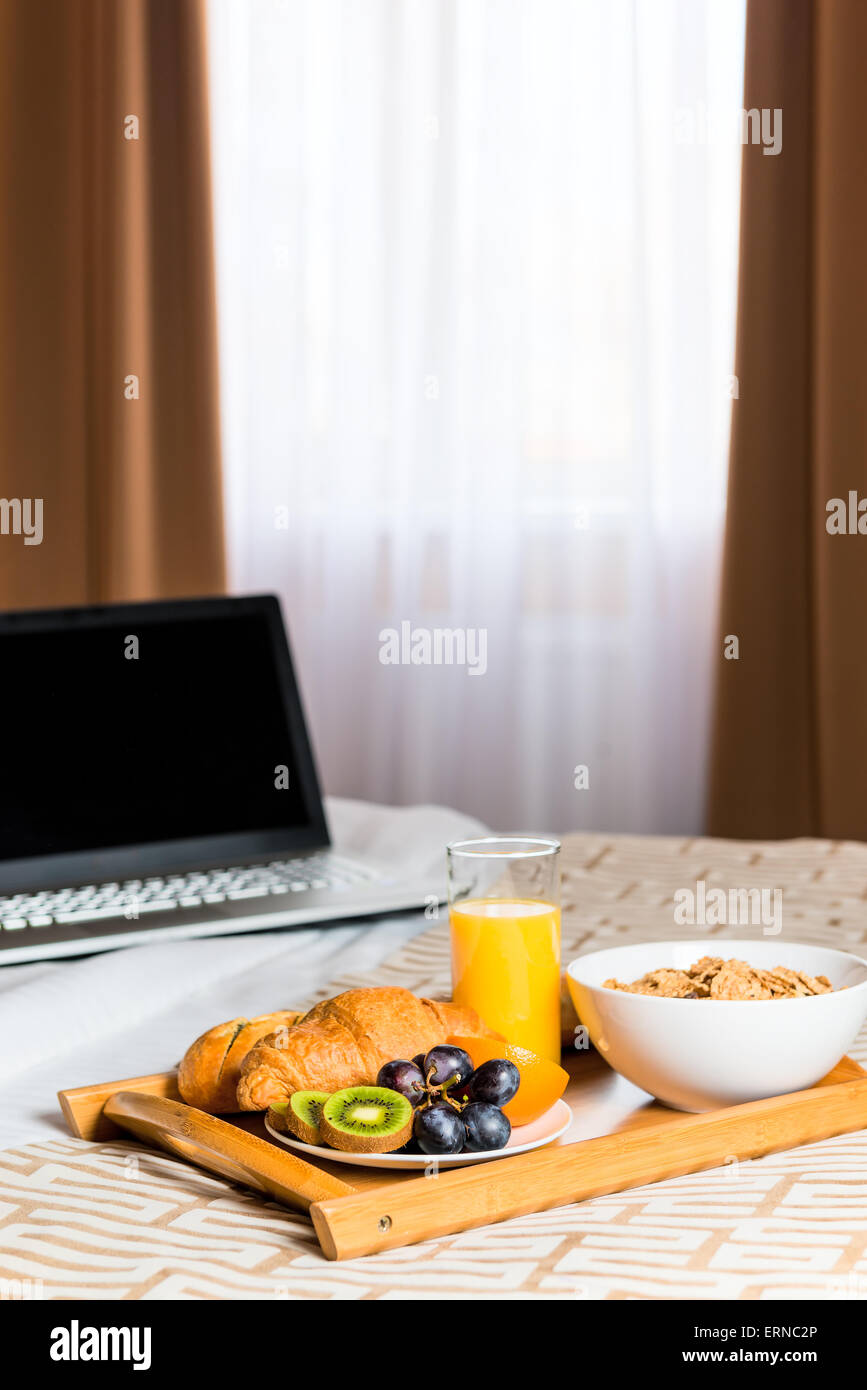 ein Tablett mit Essen auf dem Bett gegen das Fenster Stockfoto