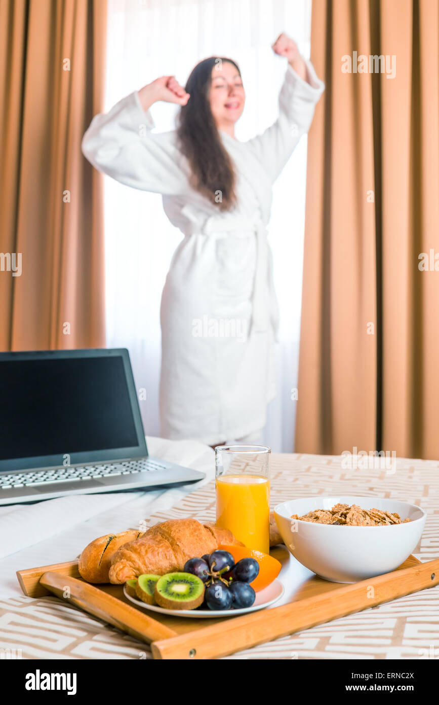 Frühstück im Bett und streckt sich eine Frau im Bademantel Stockfoto