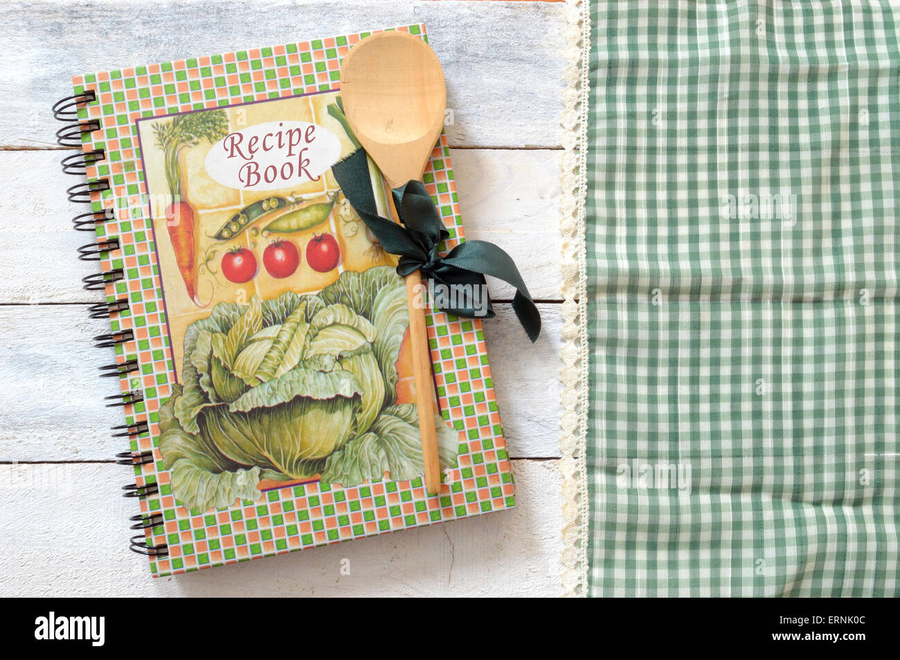 Rezeptbuch. Geschirr aus Holz Wagen auf einer grünen Tischdecke auf einem weißen Holztisch einer rustikalen Küche. Textfreiraum Stockfoto