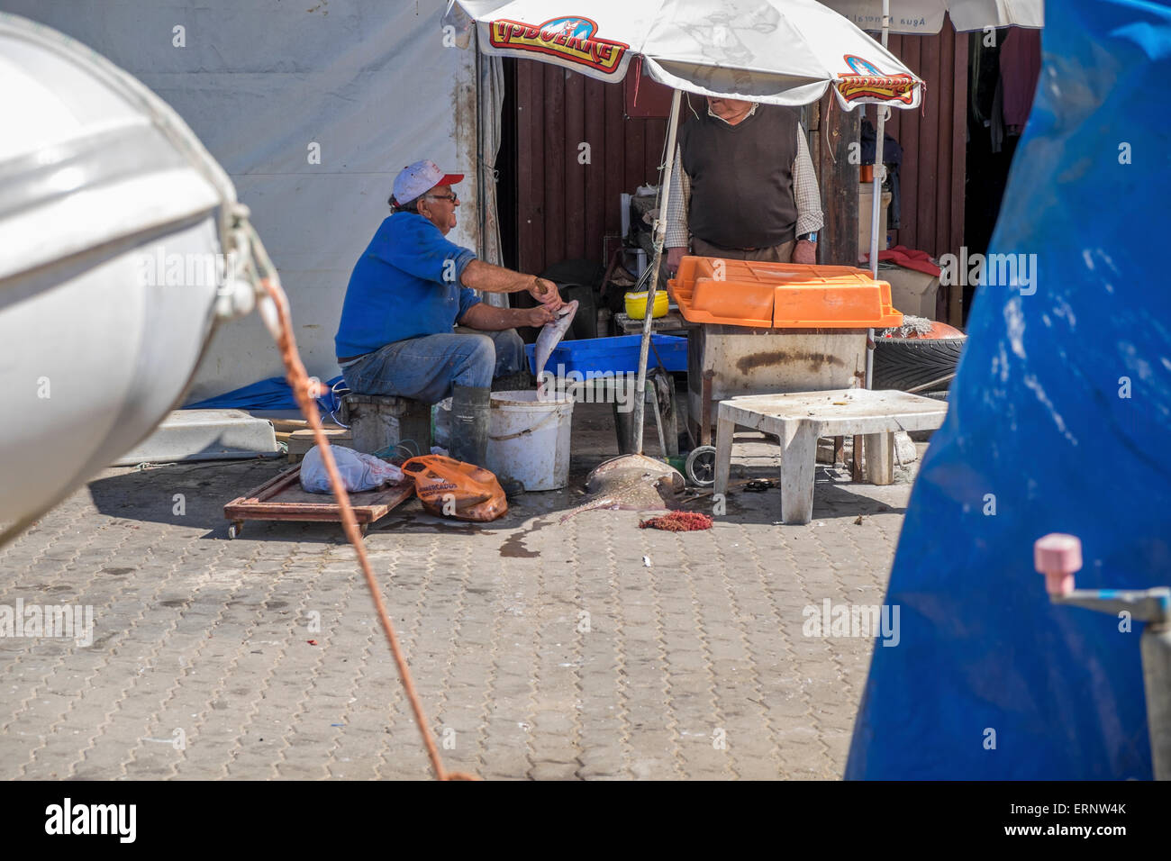 Ein Fischer saß an einem Tisch wo er Reinigung und ausnehmen der Fische, die er früher in den Tag erwischt hat Stockfoto