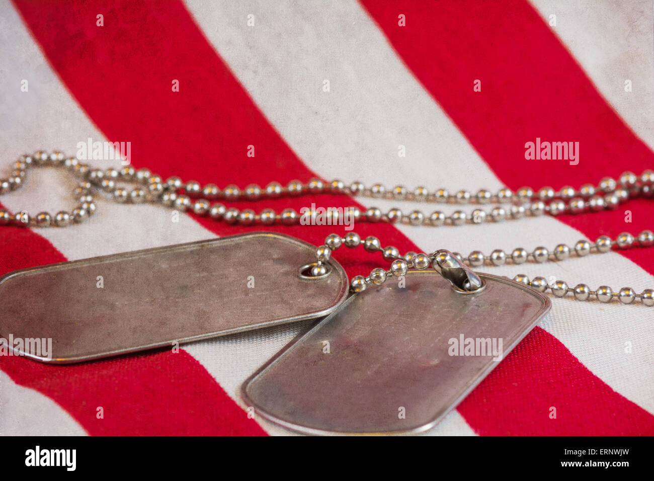 Black Dog Tags lag auf einer rot-weiß gestreifte Flagge Stockfoto