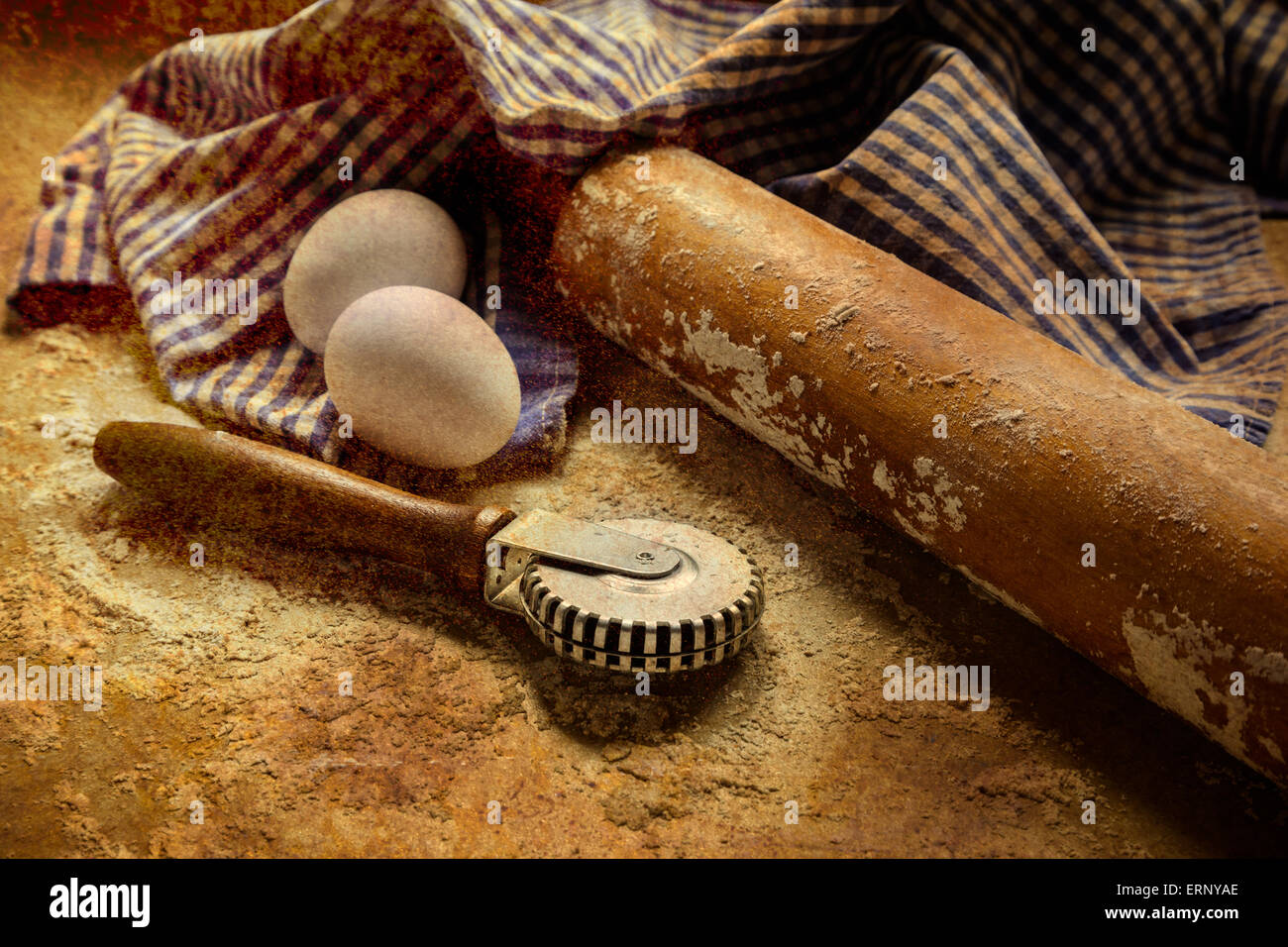 Ein antikes Nudelholz sitzt auf einer bemehlten Fläche mit zwei Eiern, ein Pie Kruste Crimper und einem karierten blauen und weißen Handtuch. Stockfoto