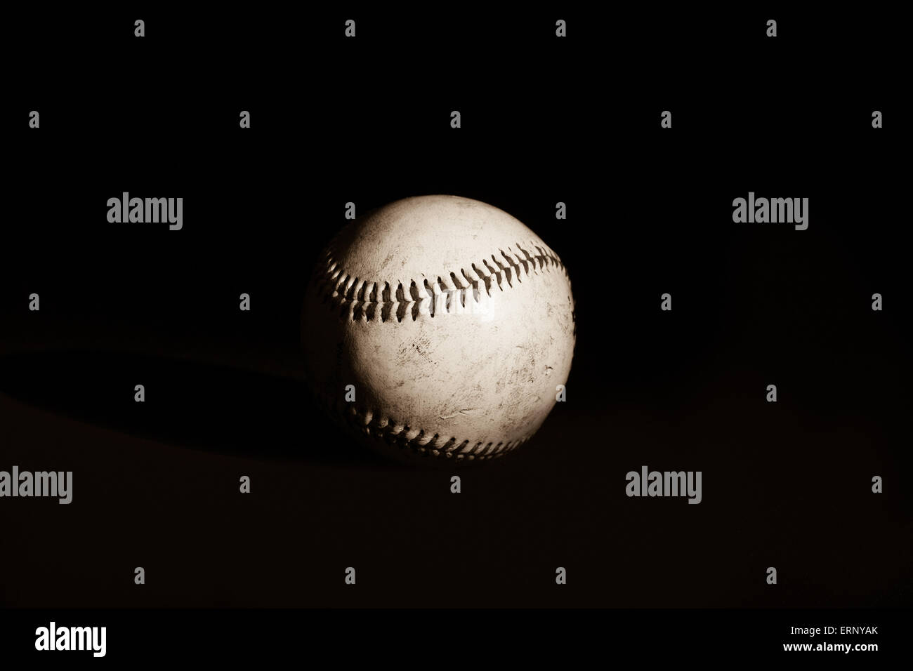 Ein Baseball mit Schattendetails sitzt auf einem einfarbigen schwarzen Hintergrund in ein Sepia Entwickler. Stockfoto