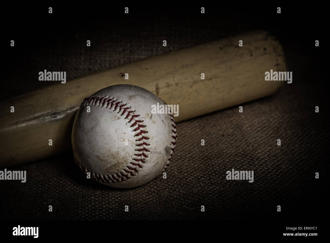 Ein abgenutzter Baseball und Fledermaus sitzen auf einer Leinwand Oberfläche.  Bild wurde mit einer Lightpainting-Technik beleuchtet. Stockfoto