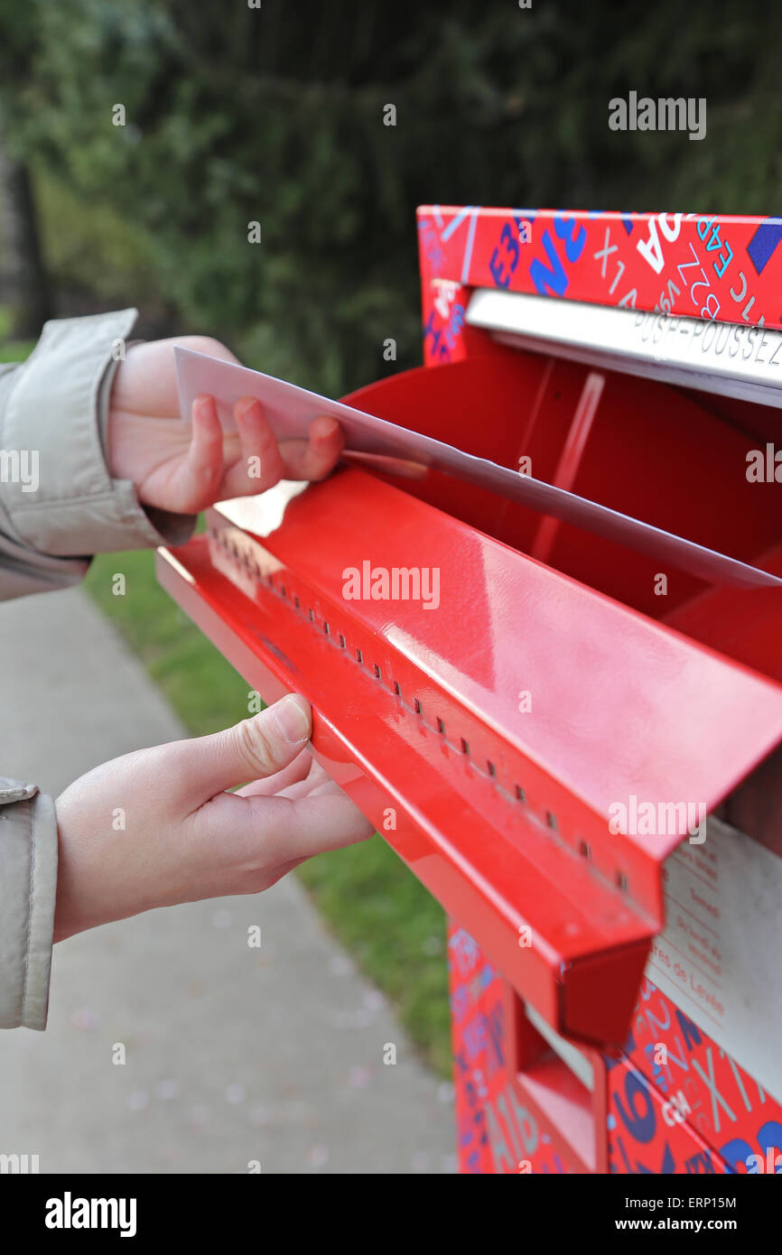 Hand eine Steuer Bericht schreiben in einen roten Briefkasten senden Stockfoto