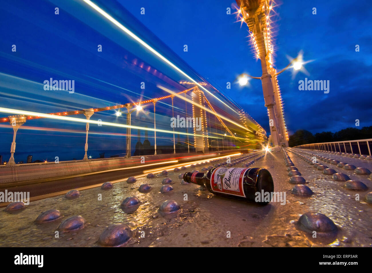 Ein Bus fährt über Chelsea Bridge mit einer Bierflasche im Vordergrund - vielleicht eine Nachricht gegen Alkohol am Steuer Stockfoto
