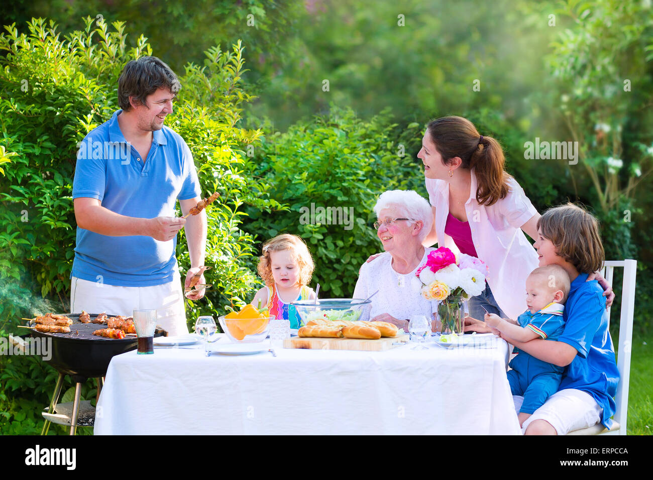Grill Garten-Grillparty. Glückliche Großfamilie Grill-Lunch mit Großmutter Verzehr von Fleisch mit Salat im Garten genießen Stockfoto