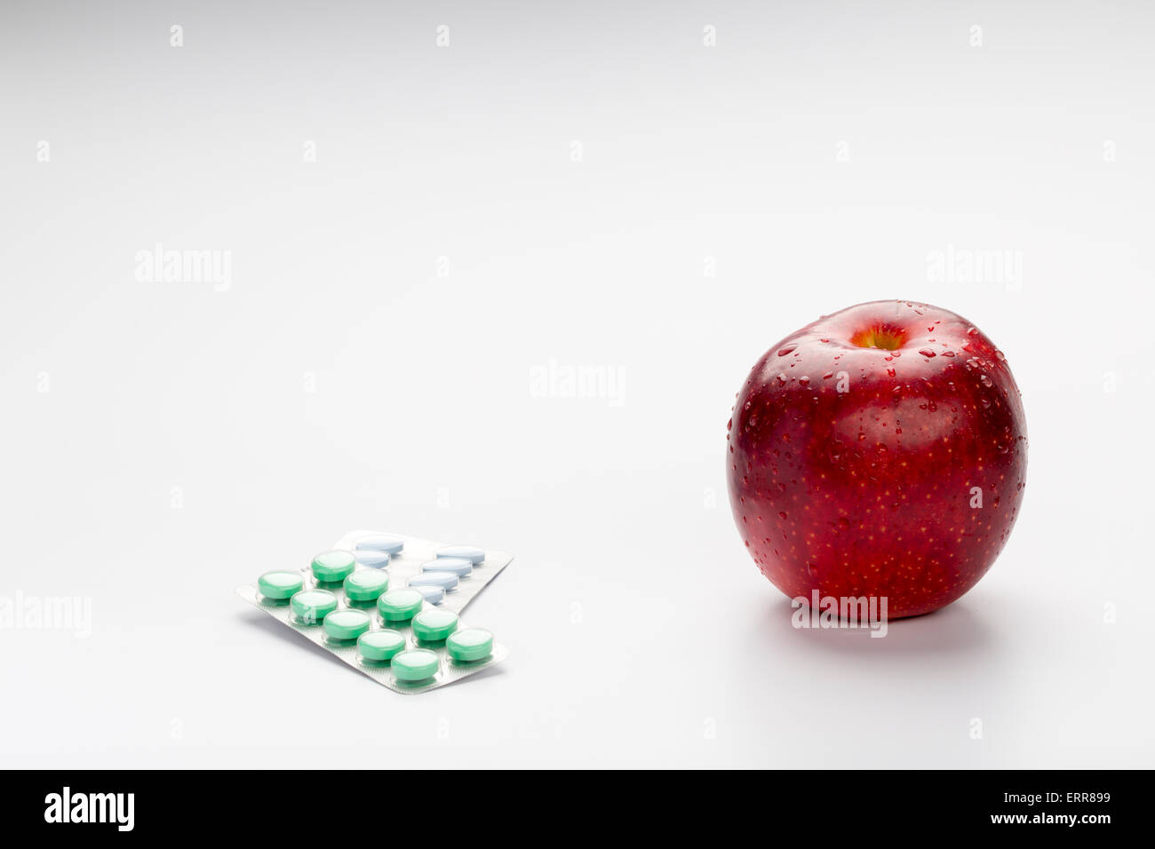 Roter Apfel und bunte Pillen im Blister auf weißem Hintergrund Stockfoto