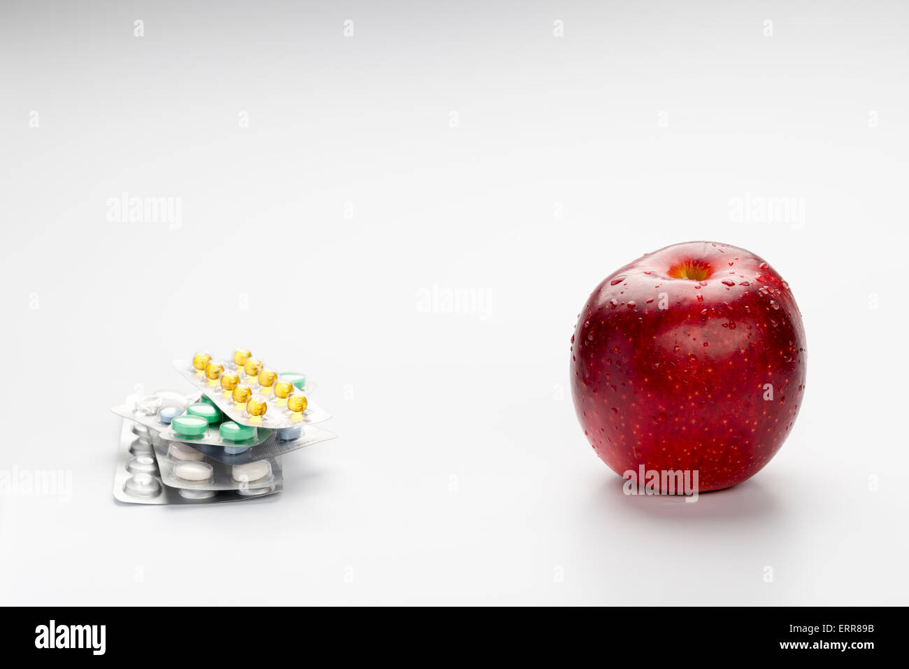 Roter Apfel und bunte Pillen im Blister auf weißem Hintergrund Stockfoto