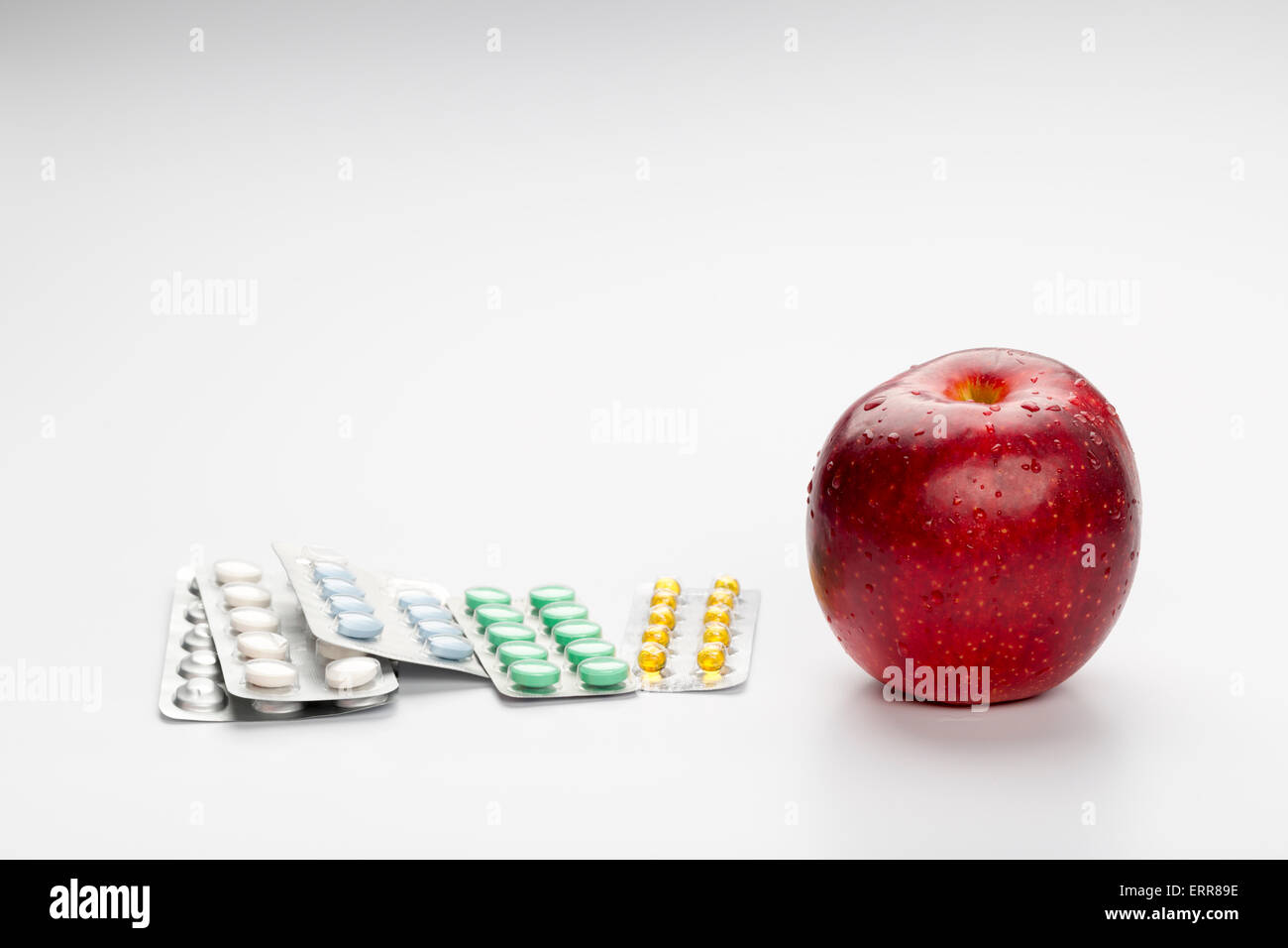 Roter Apfel und bunte Pillen im Blister auf weißem Hintergrund Stockfoto