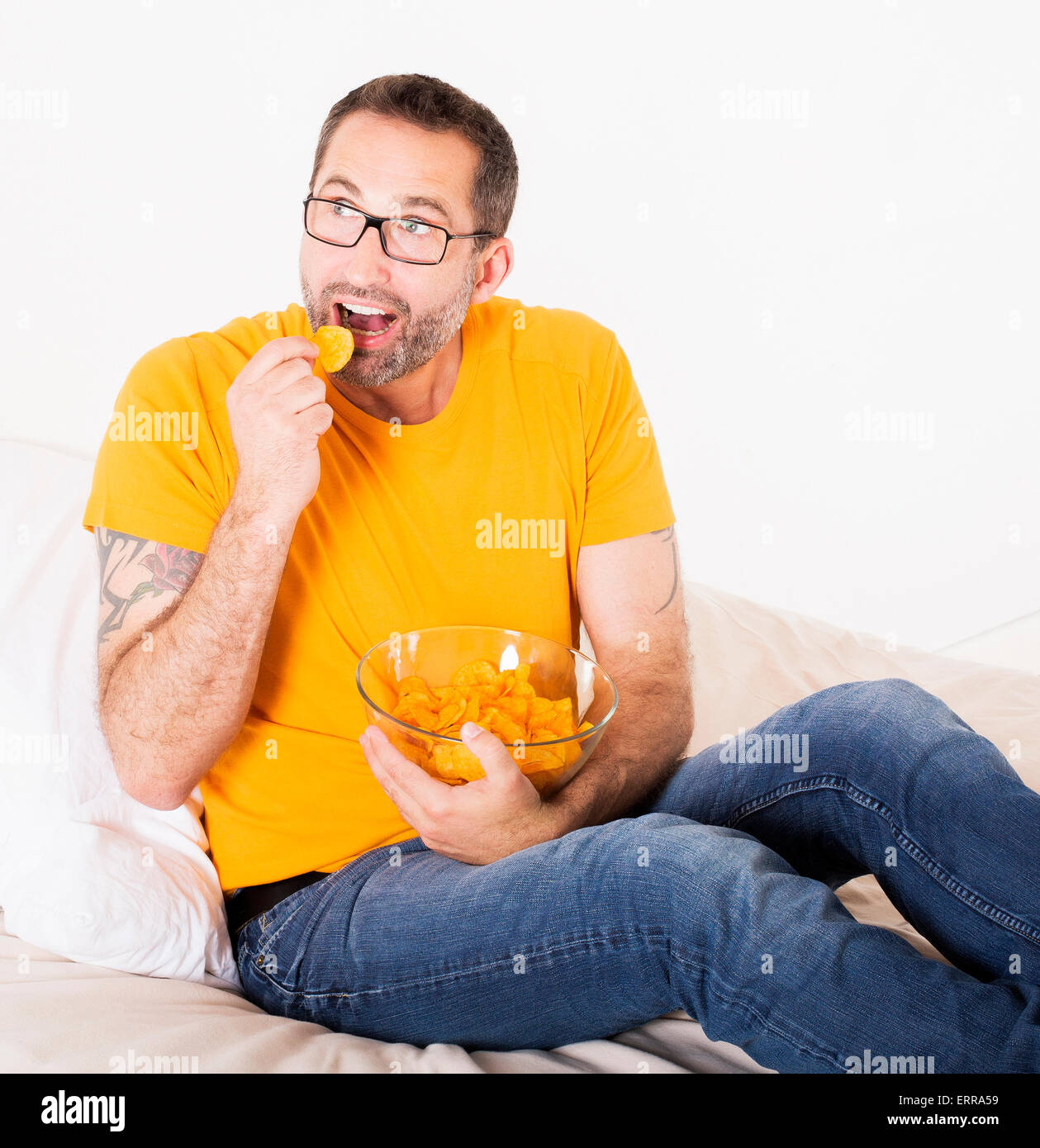 Mann mit Brille hält eine Schale mit Kartoffelchips und Essen Sie Stockfoto