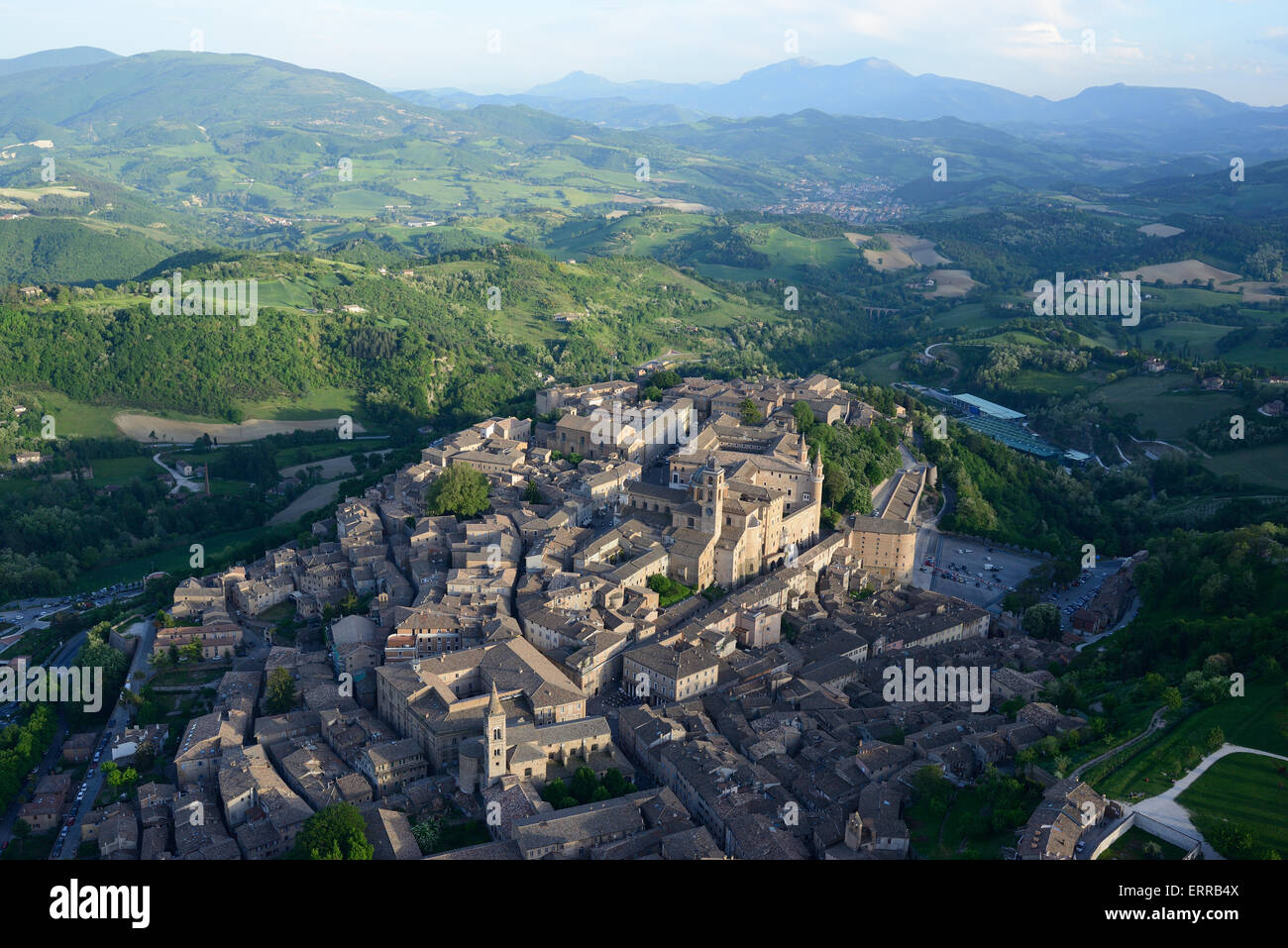 LUFTAUFNAHME. Malerische mittelalterliche Stadt in einer Umgebung von grünen Hügeln. Es ist ein UNESCO-Weltkulturerbe. Urbino, Provinz Pesaro und Urbino, Marken, Italien. Stockfoto