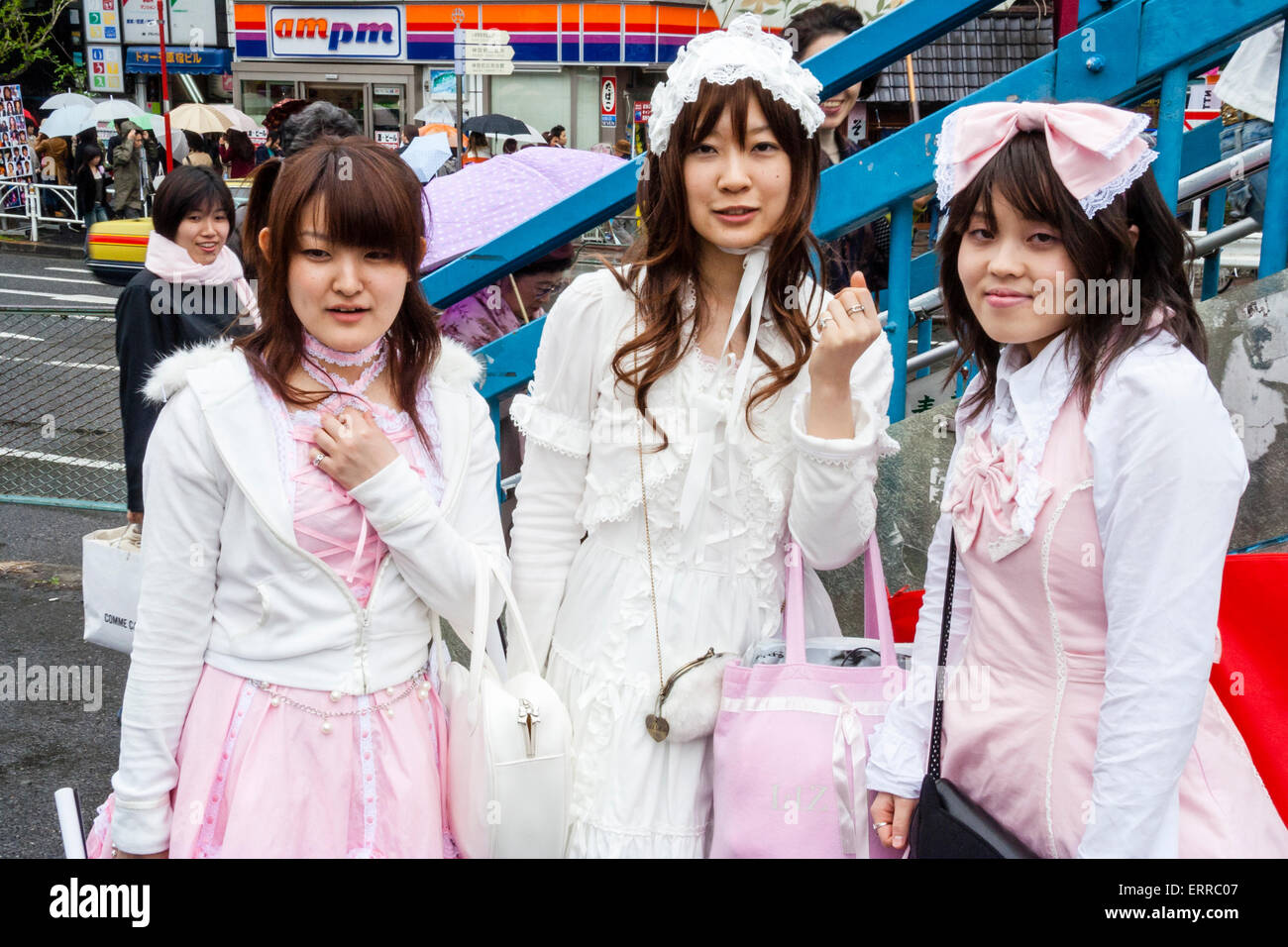Drei junge japanische Frauen kleideten sich in "Sweet Lolita" Classic Lolita Stil pinkfarbene Maid Kostüme, beeinflusst von Victoria-Kleidung. Blickkontakt, Augenkontakt. Stockfoto