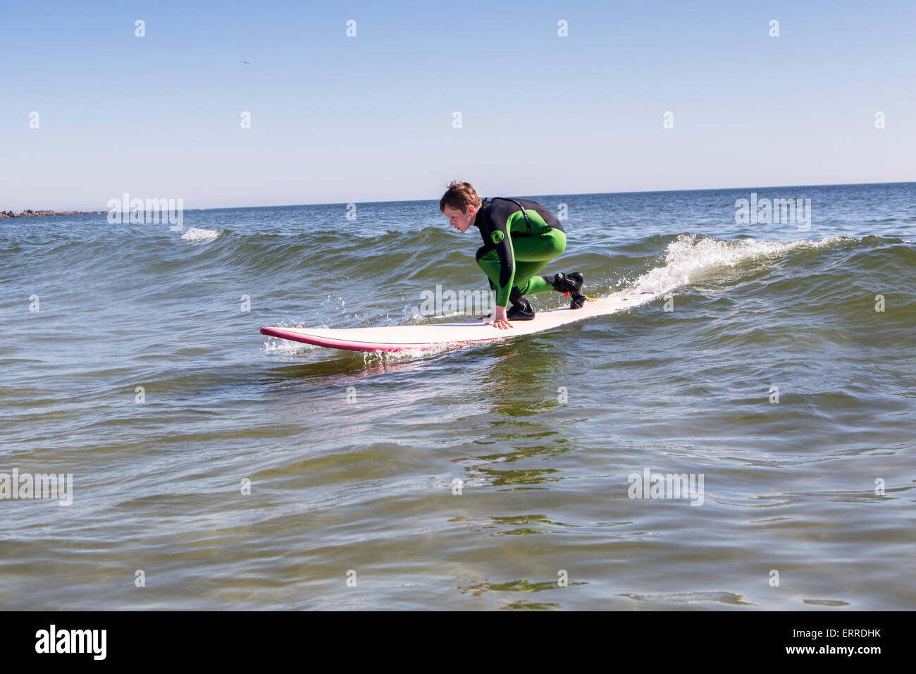 kleiner Junge im grünen Neoprenanzug Surfen lernen Stockfoto