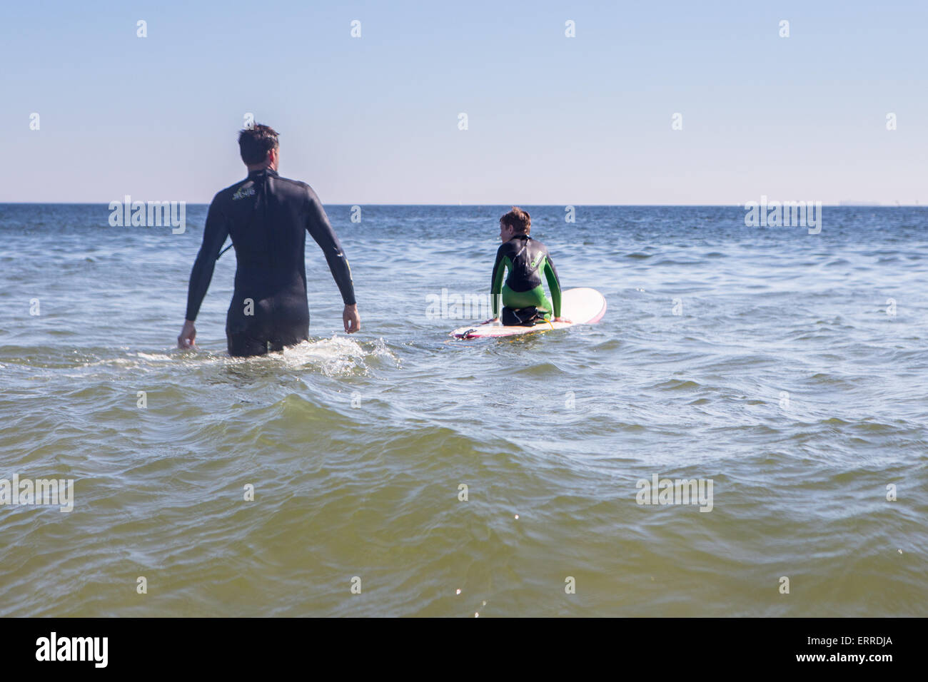 Vater und Sohn mit Rücken drehte waten in den Ozean zum Surfen Stockfoto