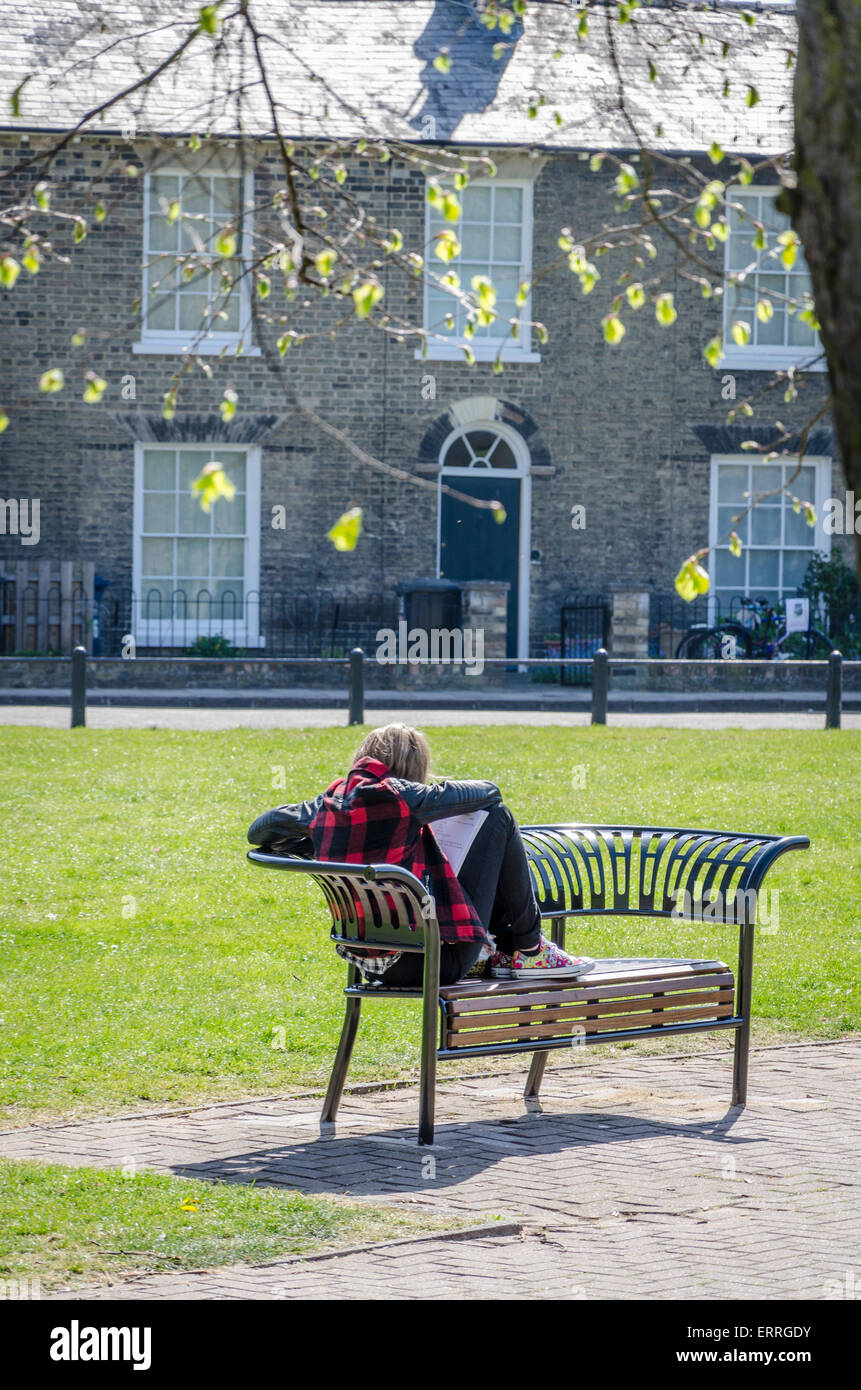 Junge Frau saß auf einer Bank in New Square Park, Cambridge, UK Stockfoto