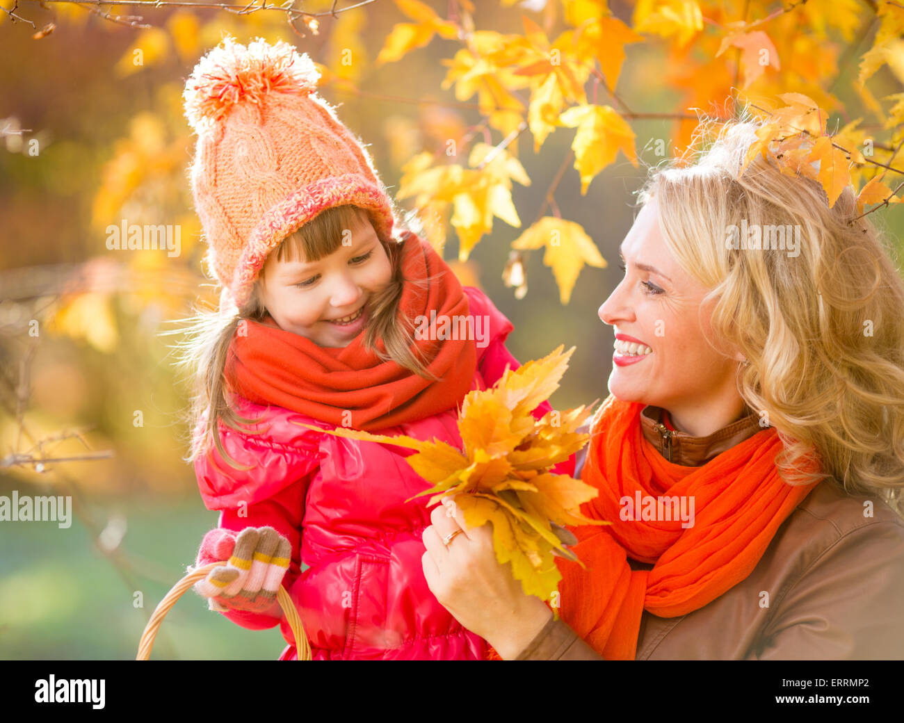 Lächelnde Mutter und Kind im Freien mit gelben Blätter im Herbst Stockfoto