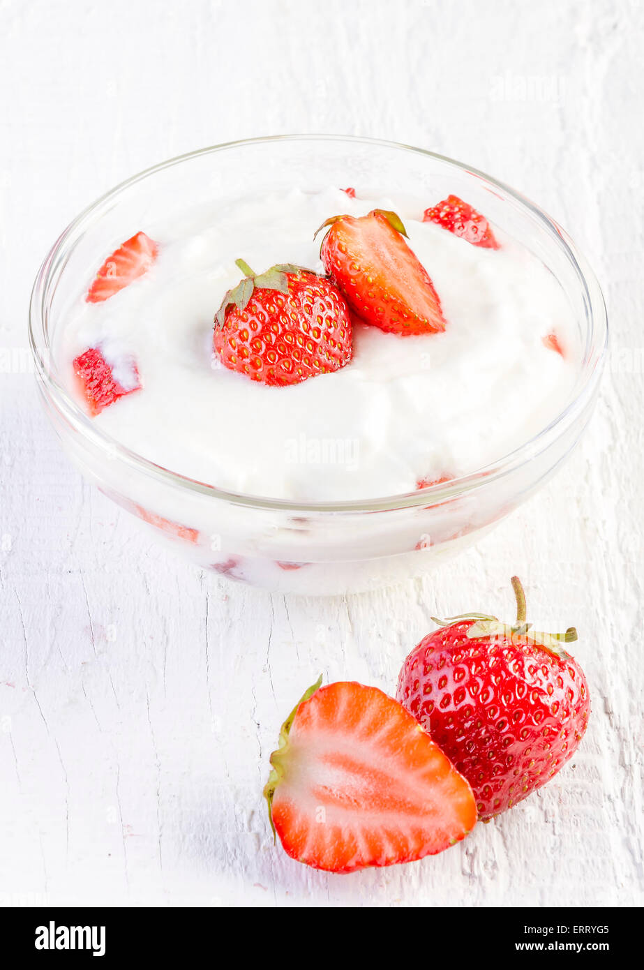 frische Bio-Joghurt mit Erdbeeren auf weißem Hintergrund aus Holz Stockfoto