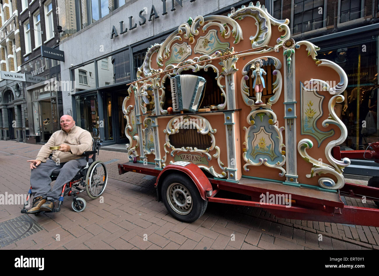 Einen behinderten Mann auf der Suche nach Spenden neben eine Dampforgel in Amsterdam, Holland Stockfoto