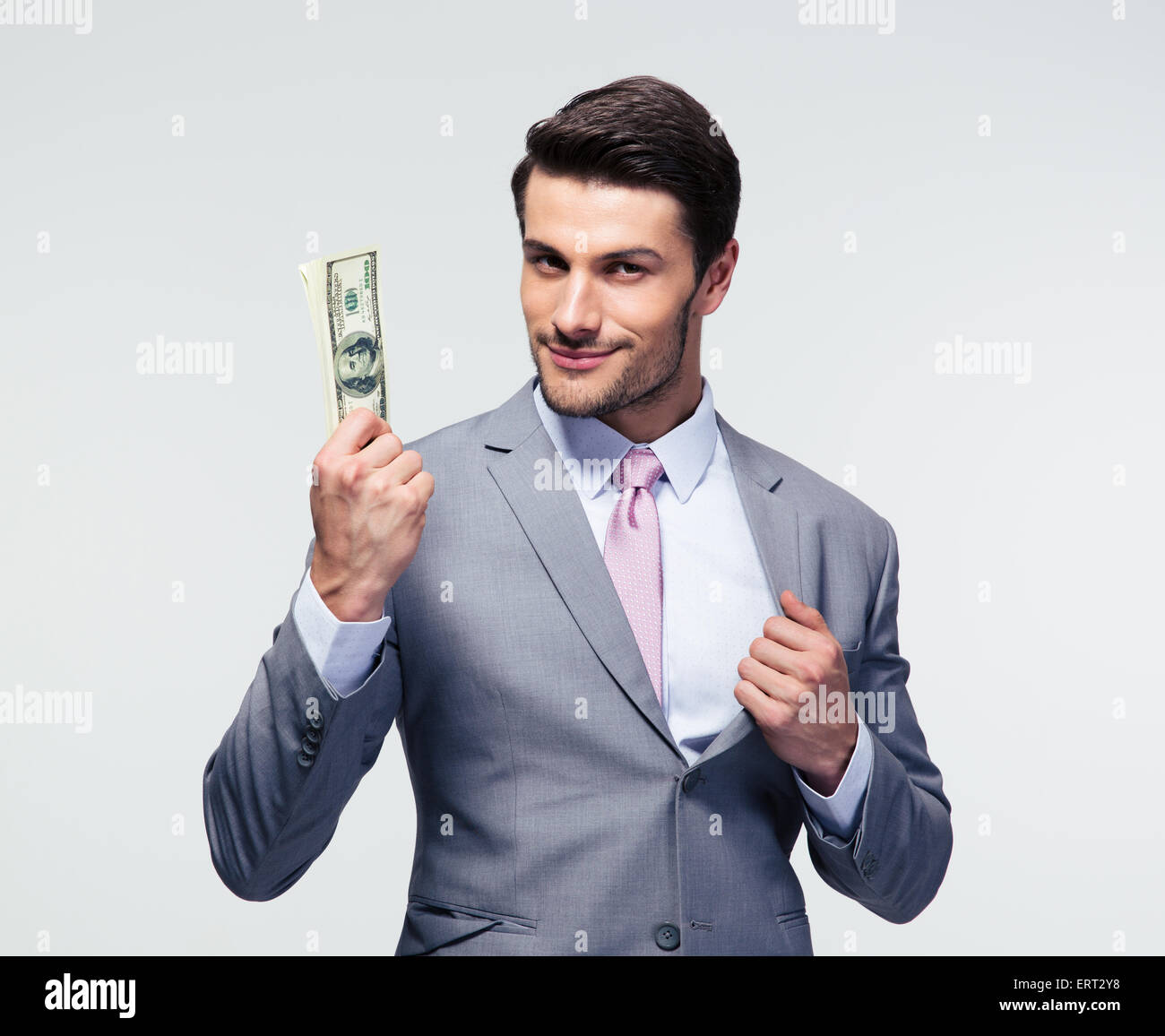 Glücklich Geschäftsmann hält uns Dollar auf grauem Hintergrund. Blick in die Kamera Stockfoto