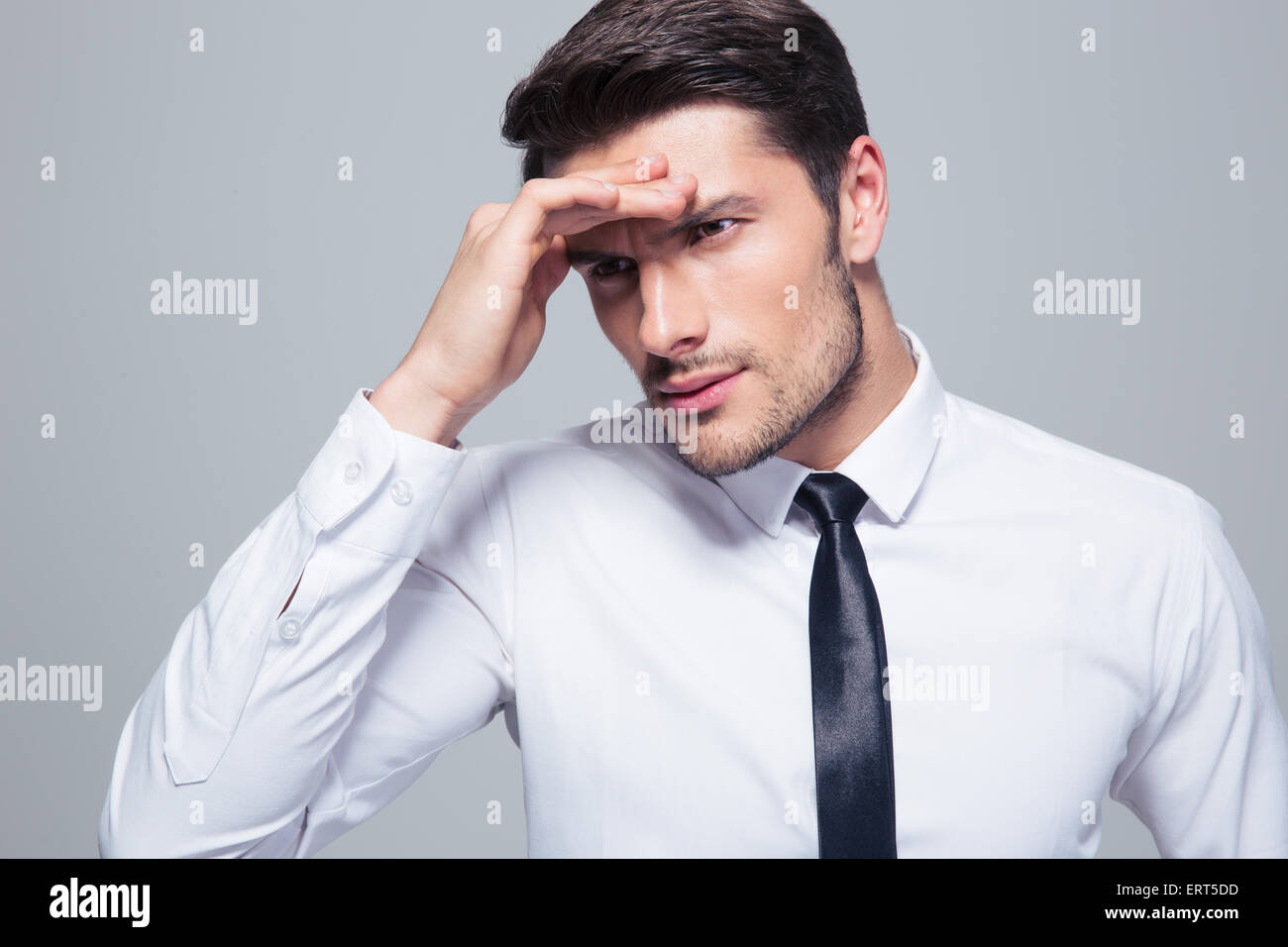 Porträt eines Geschäftsmannes mit Kopfschmerzen auf grauem Hintergrund Stockfoto