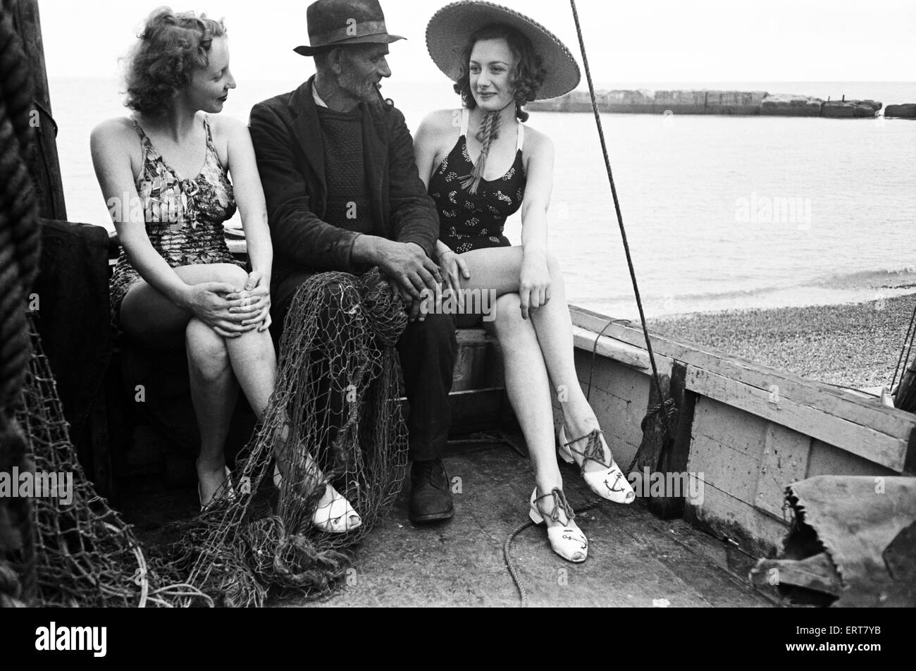 Frauen in ihren sitzen in einem Fischerboot mit einem Fischer an der Küste, Hastings, ca. 1945 Baden-Kostümen. Stockfoto