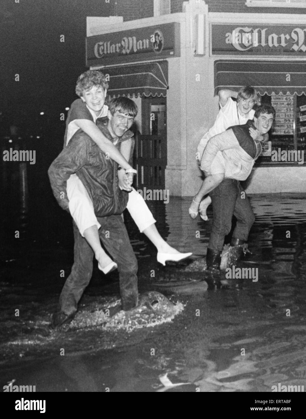 Weiter flussaufwärts an der Kreuzung der "Römerstraße" und Rockliffe Straße Middlesbrough nach einem lokalen Flut. Lokalen Jungs helfen den Mädchen auf der überfluteten Straße 22. Juni 1983 Stockfoto