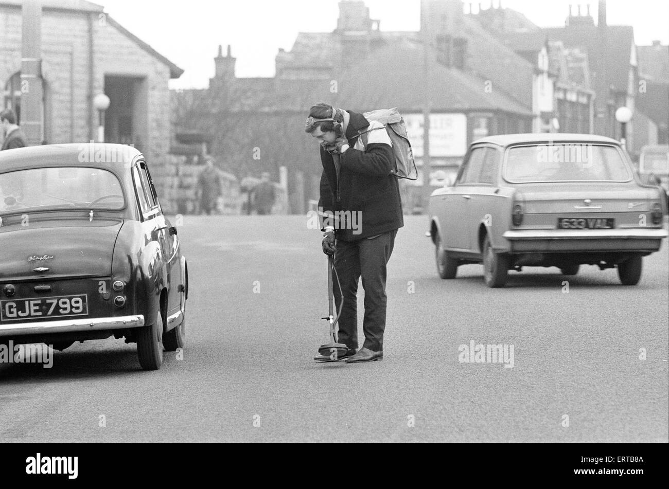 Roger Eyre, Assistant Engineer in der Ausbildung mit der Urban District Council, Sutton in Ashfield, Notts, mit aufgelösten Minensuchgerät Schachtabdeckungen finden durch Schichten aus Asphalt als Straße fallenden waren eilig, 26. Januar 1968 wieder aufgetaucht. Stockfoto Roger Eyre, Assistant Engineer in der Ausbildung mit der Urban District Council, Sutton in Ashfield, Notts, mit aufgelösten Minensuchgerät Schachtabdeckungen finden durch Schichten aus Asphalt als Straße fallenden waren eilig, 26. Januar 1968 wieder aufgetaucht. Stockfoto
