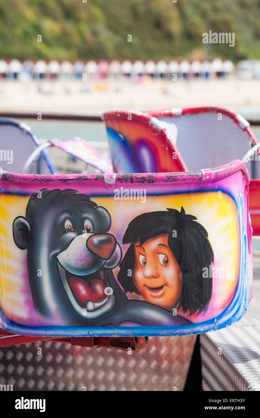 Baloo & Mowgli aus dem Dschungelbuch auf Festplatz fahren am Bournemouth Pier mit Strandhütten und Strand im Hintergrund, Bournemouth Stockfoto