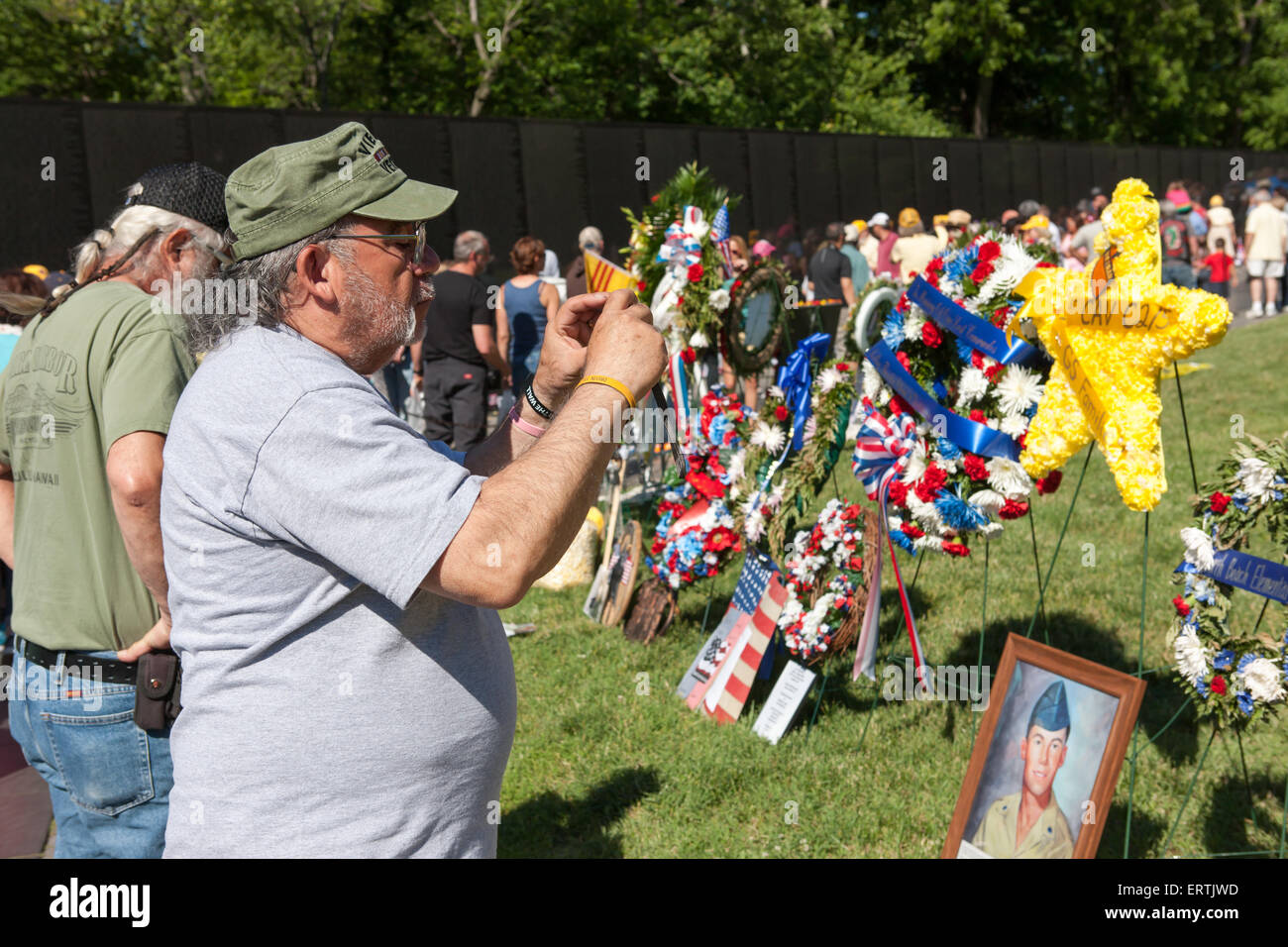 Eine Vietnam-Veteran rastet ein Bild von Kränzen, während andere Besucher auf das Vietnam Veterans Memorial in Washington, DC-Namen anzeigen. Stockfoto