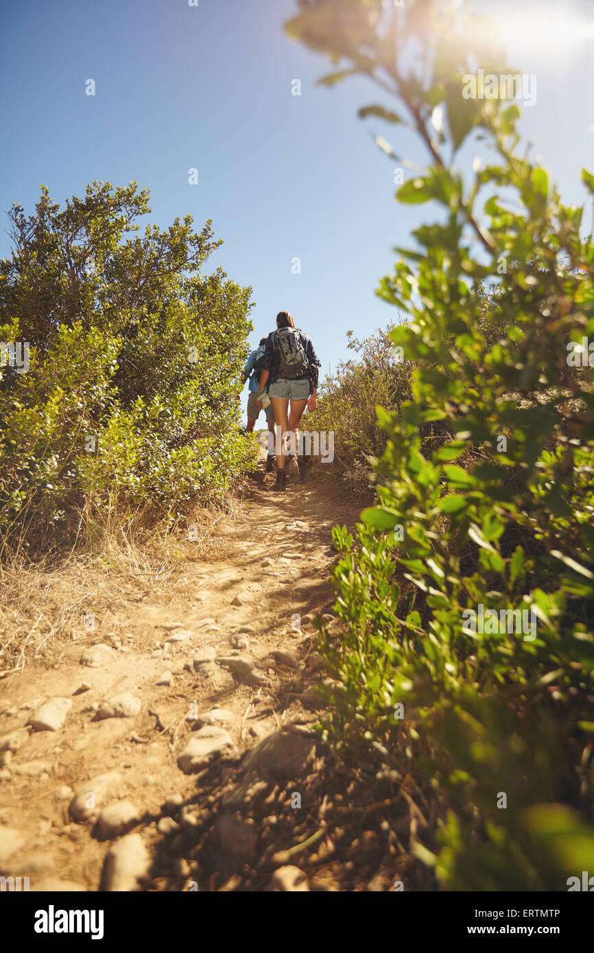 Bild von Menschen zu Fuß durch Bergweg. Rückansicht Schuss des Paares Wandern auf unbefestigten Weg durch Rasen und Pflanzen auf mountai Stockfoto