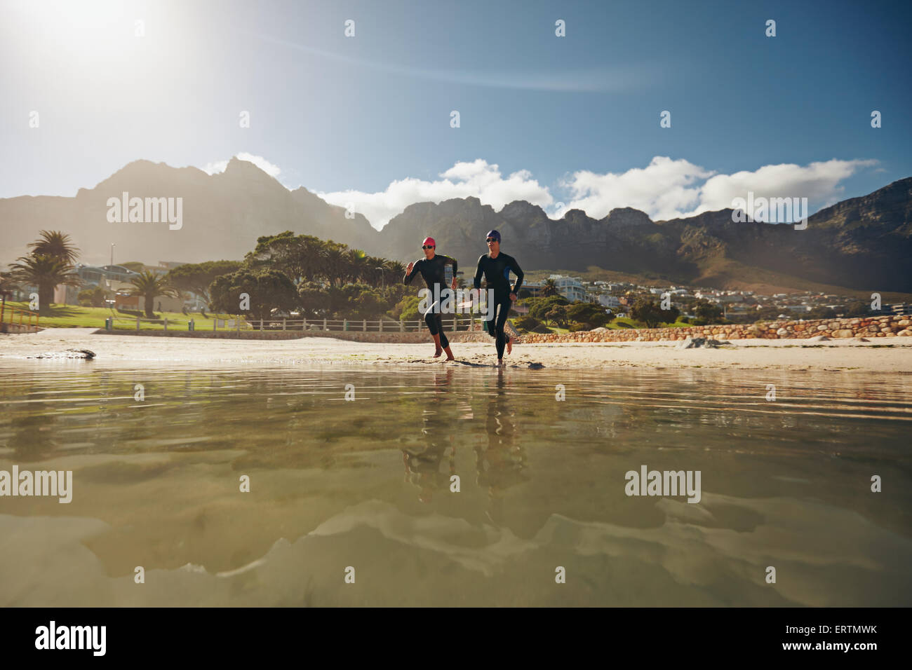 Aufnahme von zwei Athleten ins Wasser, laufen üben für Triathlon-Wettkampf. Junger Mann und Frau in Neoprenanzüge Vorbereitung fo Stockfoto