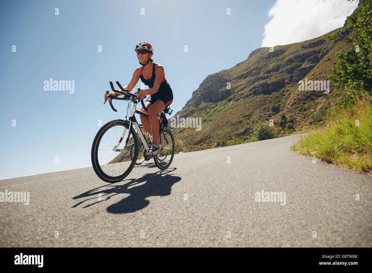 Frau im Radsport Bein einen Triathlon mit Konkurrenten im Wettbewerb. Triathleten mit Fahrrad auf offener Straße. Stockfoto