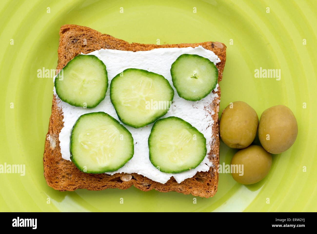 drei Oliven und gebratenen Toast mit Käse und Gurken Scheiben auf Teller grün Stockfoto