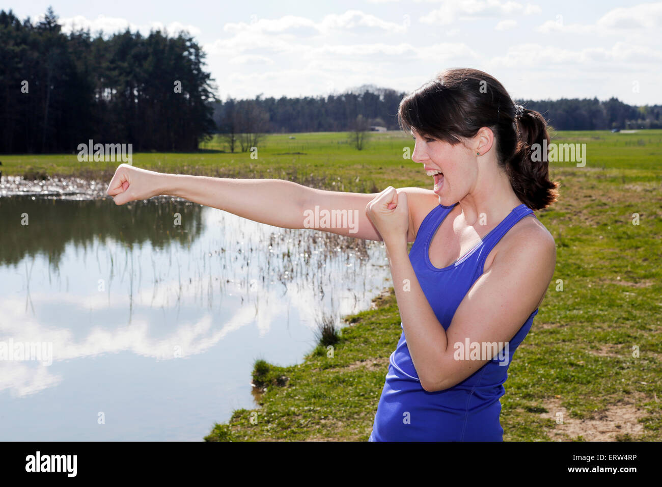 junge Frau, die an einem See und in Boxer-pose Stockfoto